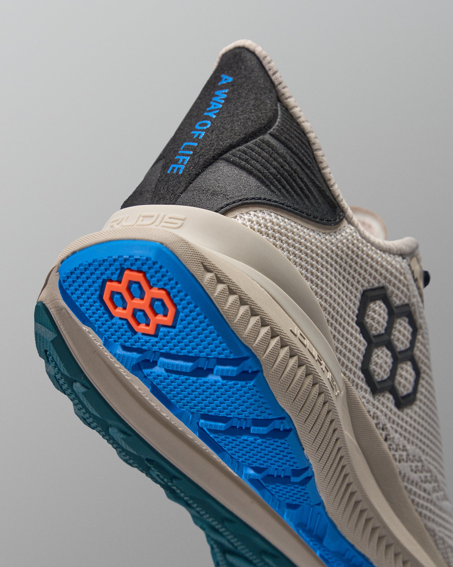 Beige training shoe with blue sole and black accents on a gray background