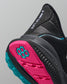 Black sneaker with pink and teal sole on a gray background