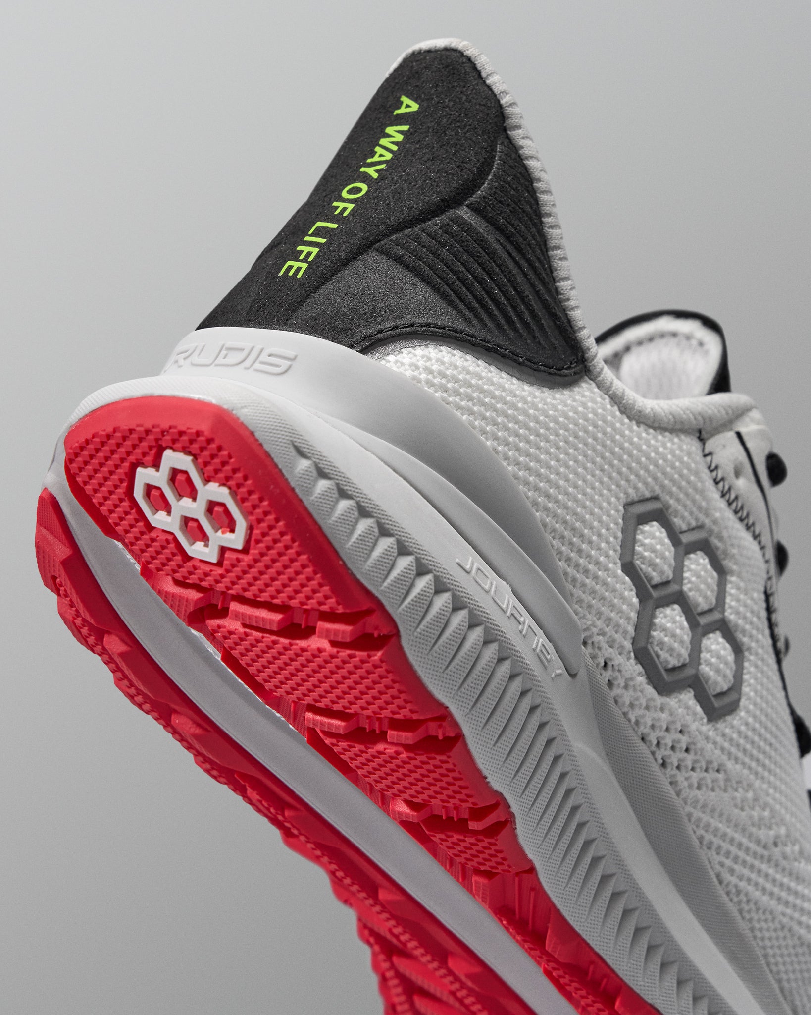 Gray and red running shoe with visible brand logos on a gray background