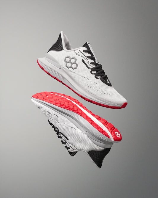 White running shoes with red soles on a gray background