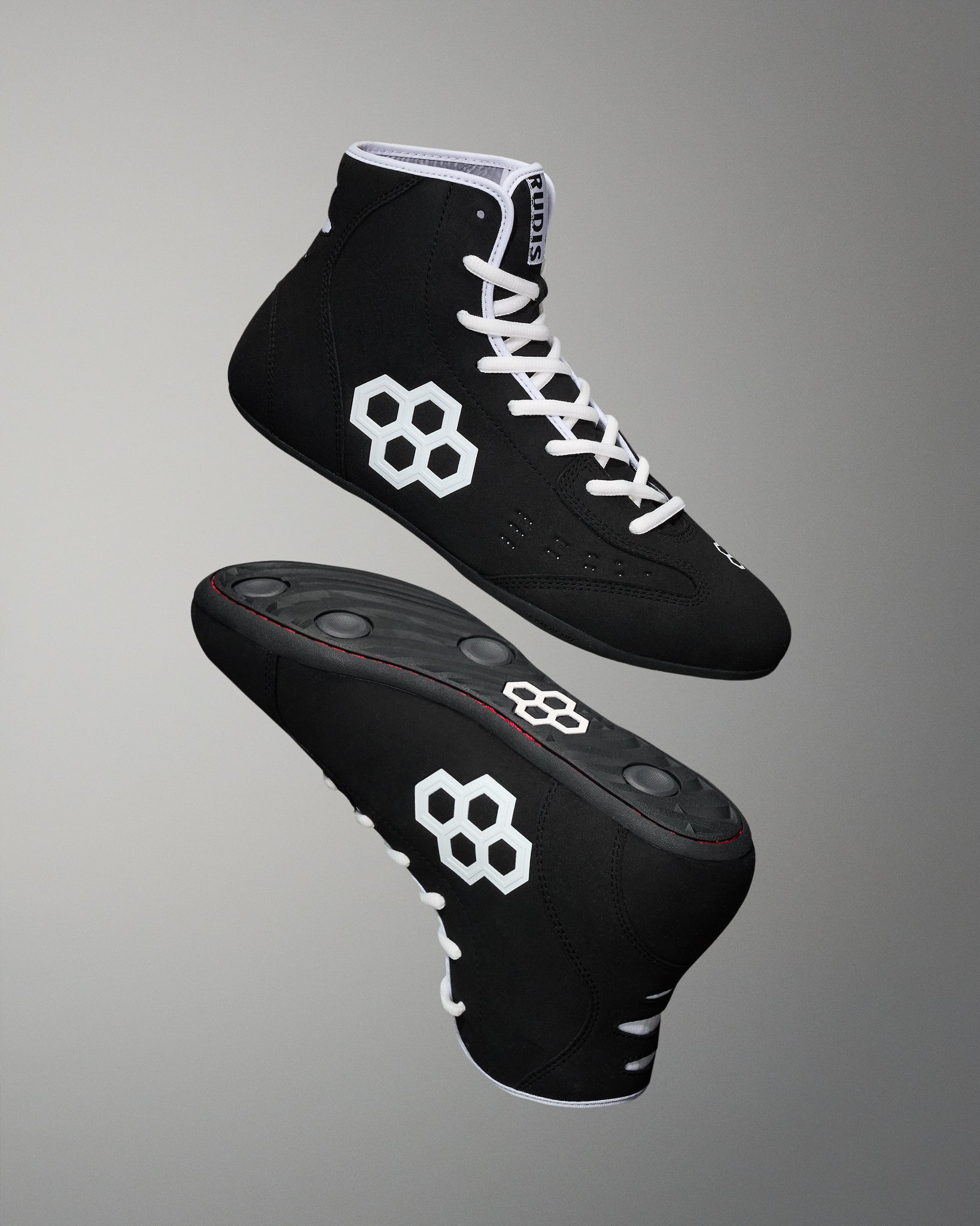 Hero image of the RUDIS international wrestling shoe - black/white on a grey background. 