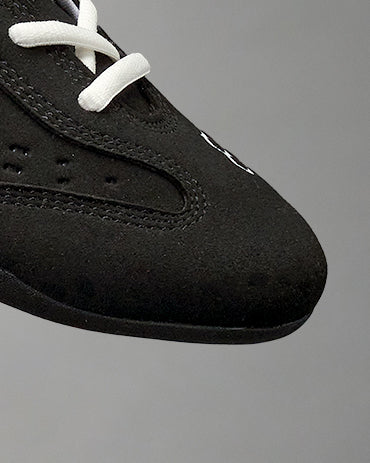 Up close toe image of the RUDIS international wrestling shoe - black/white on a grey background. 