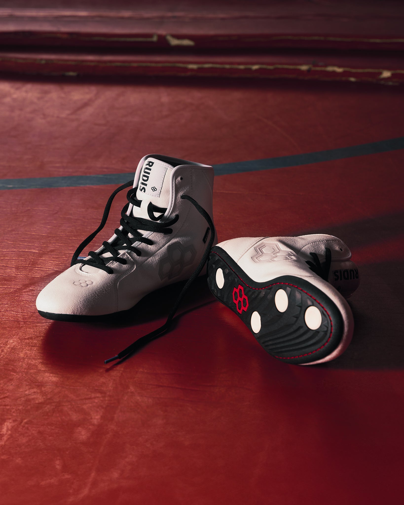 White RUDIS International Wrestling Shoes  sitting on a red wrestling mat
