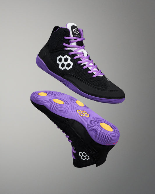 Black high-top sneakers with purple laces and soles on a gray background