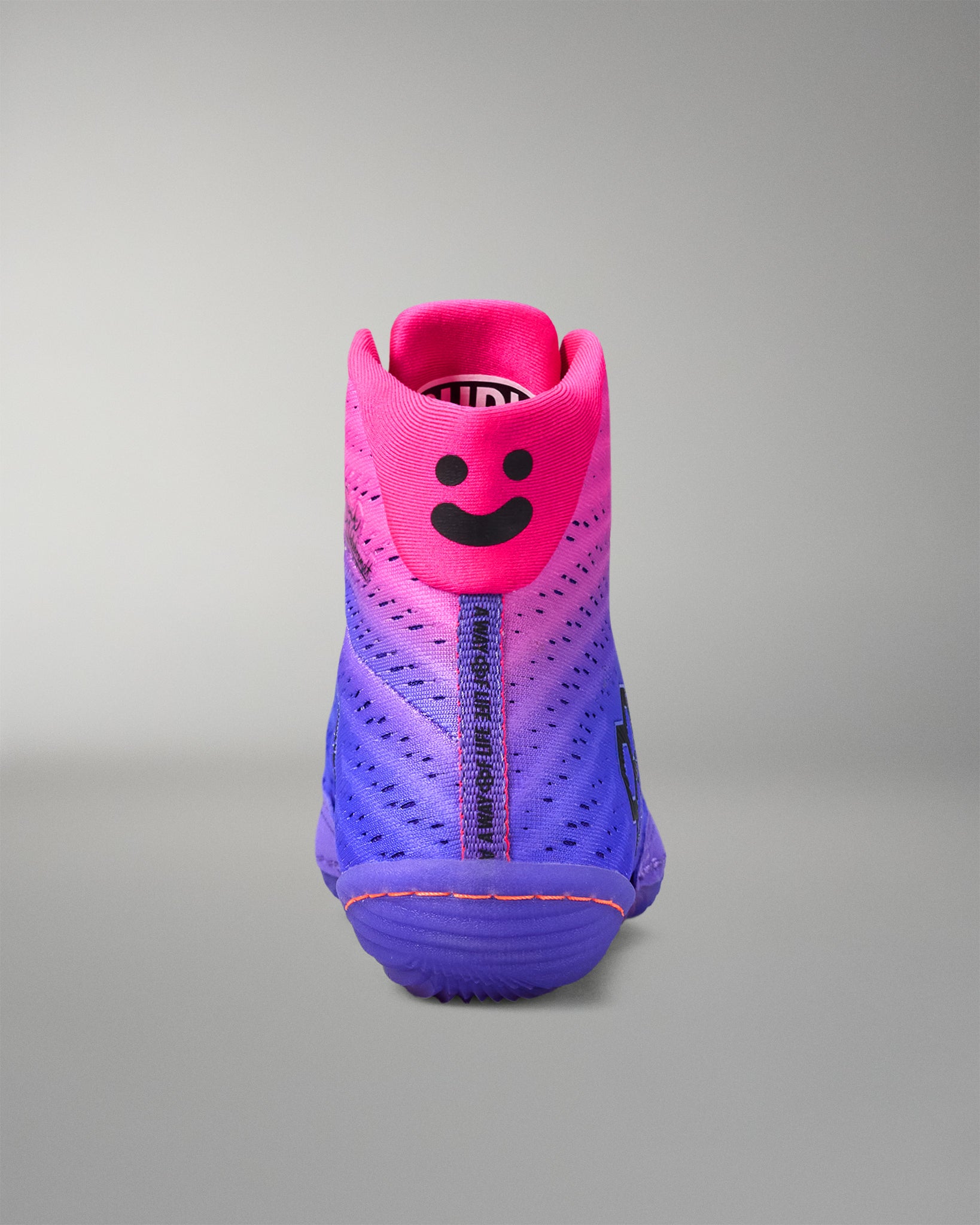 Pink and purple wrestling shoe with a smiley face design on a gray background