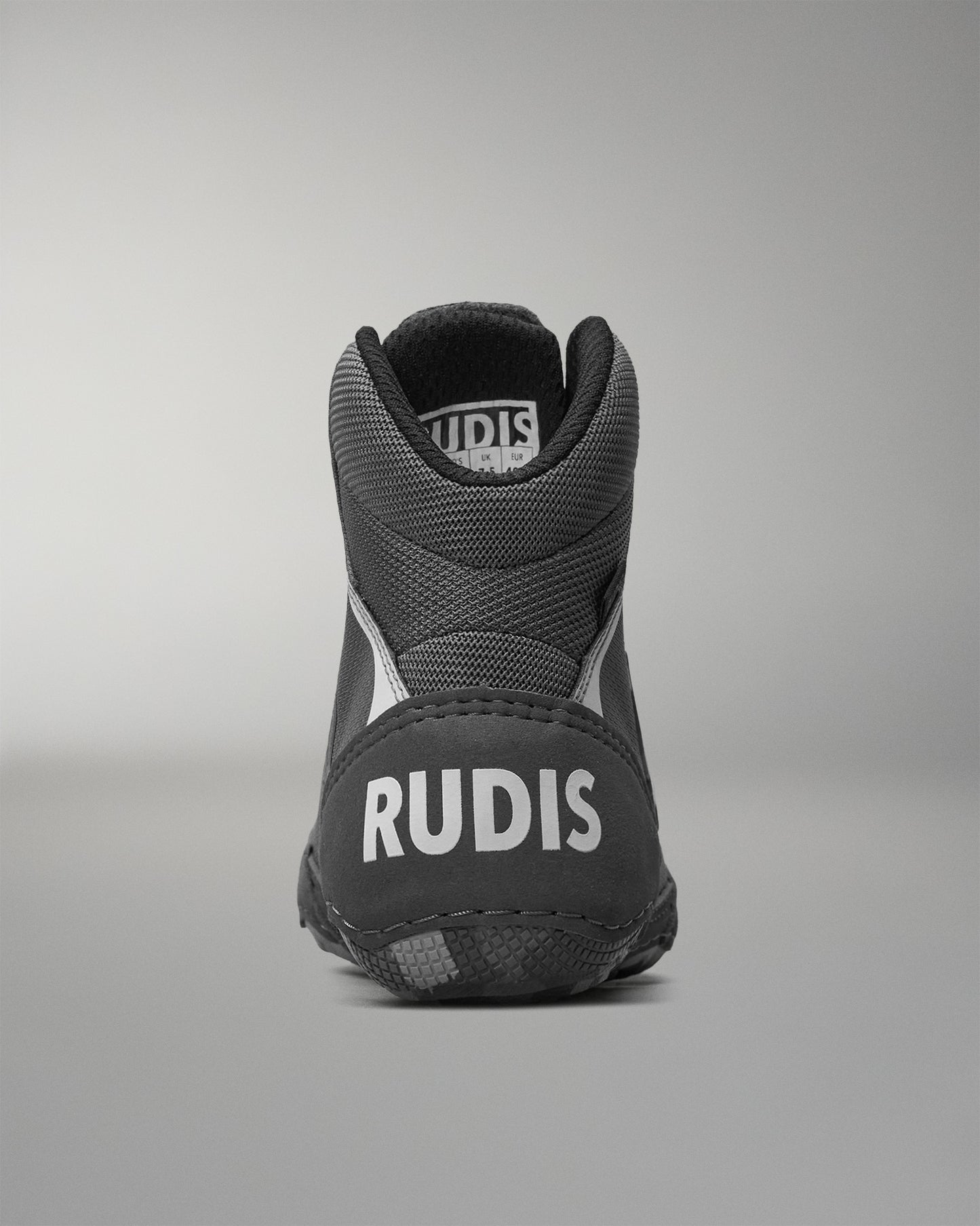 Black wrestling shoe with 'RUDIS' branding on a gray background