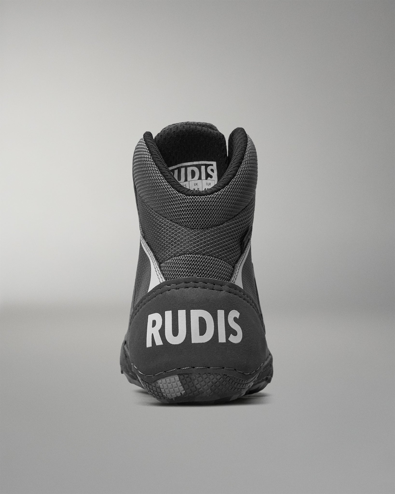 Black wrestling shoe with 'RUDIS' branding on a gray background