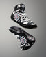 A pair of high-top athletic wrestling shoes shown from the front and side against a neutral gray gradient background. The shoes feature a black, white, and gray geometric pattern with pink and light blue graphic accents on the sides and a white flower logo on the tongue.