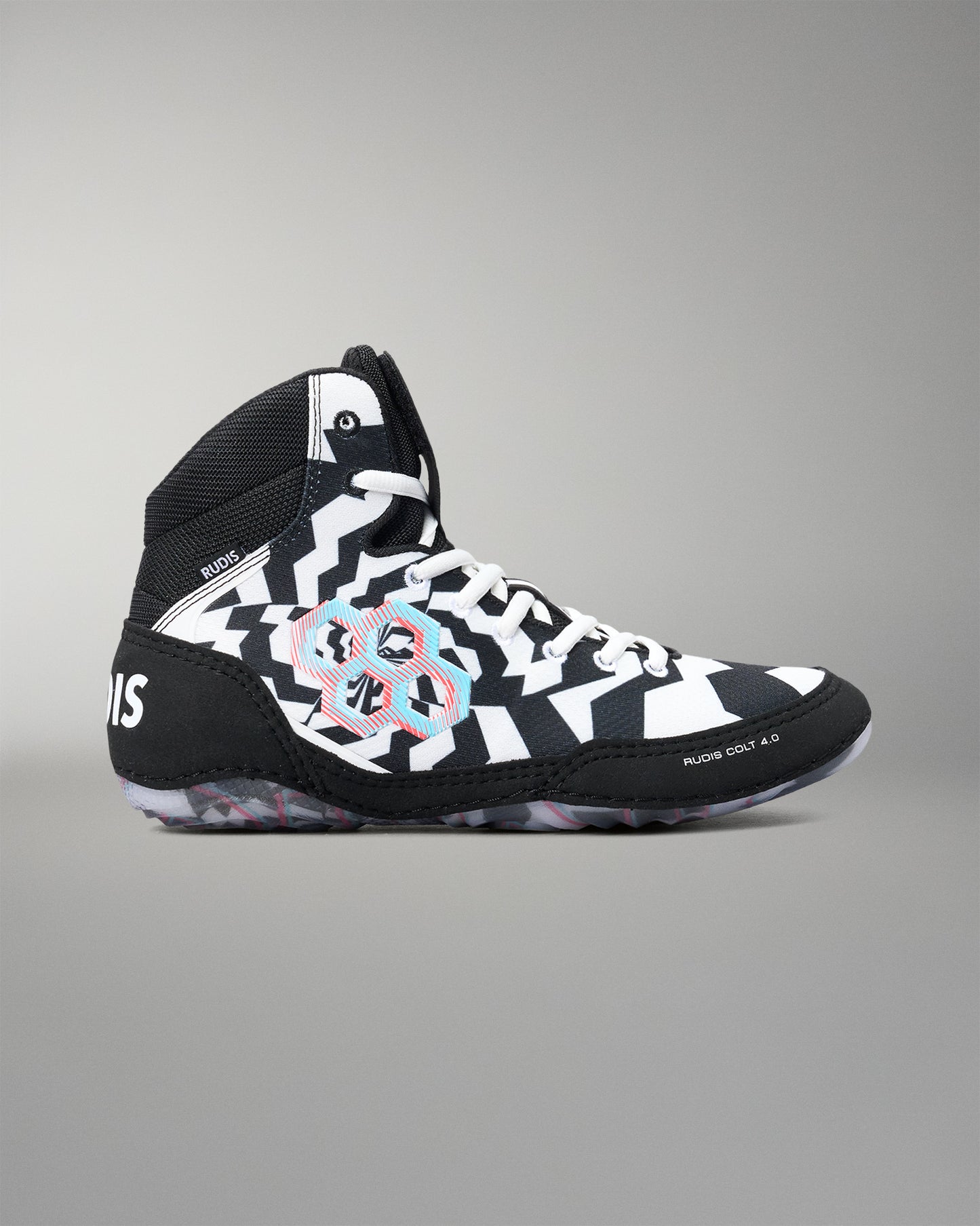 A high-top athletic wrestling shoe in black and white with a bold geometric pattern and a colorful circular graphic on the side, shown against a neutral gray background.
