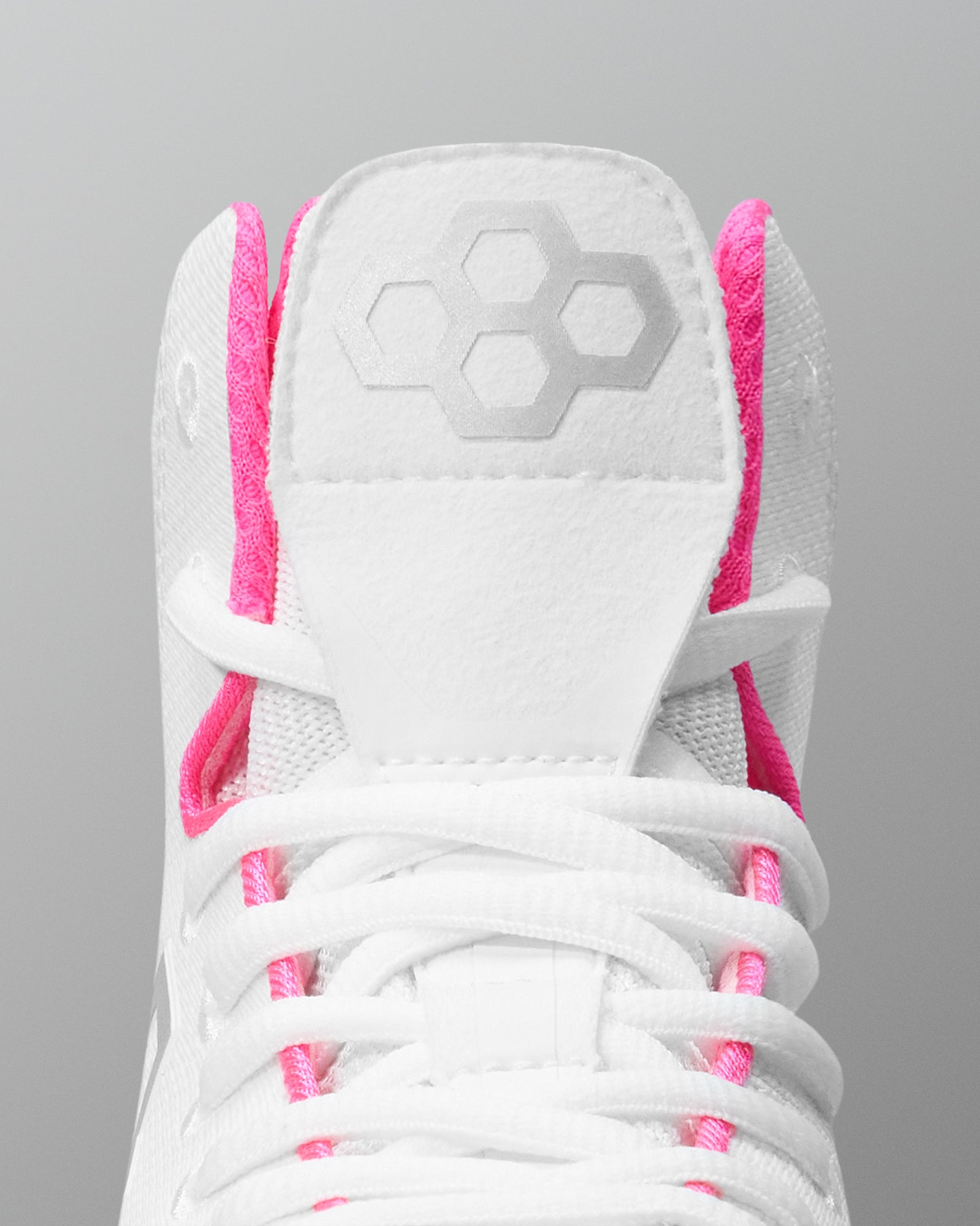 White wrestling shoe with pink accents on a gray background