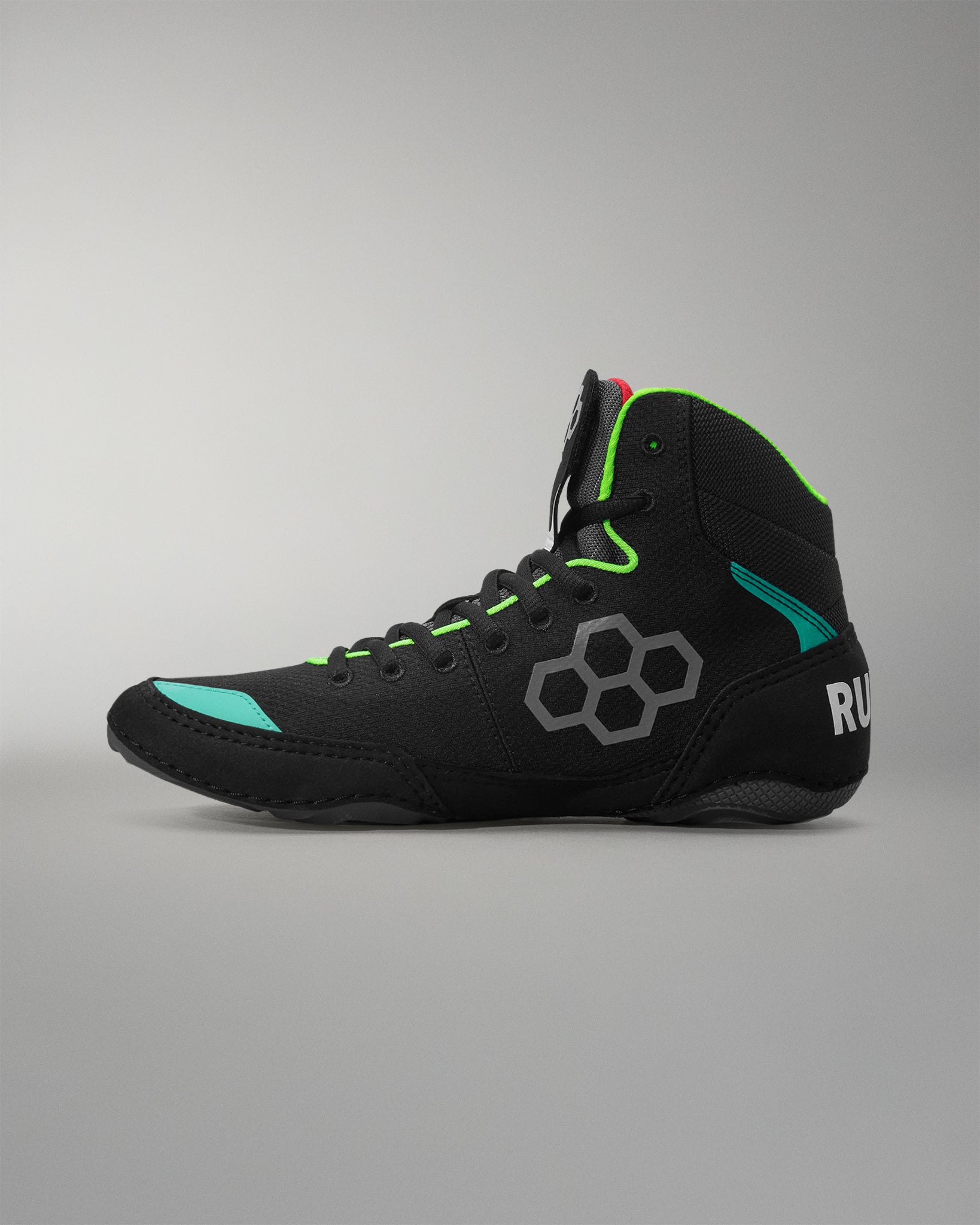 Black wrestling shoe with green accents on a gray background
