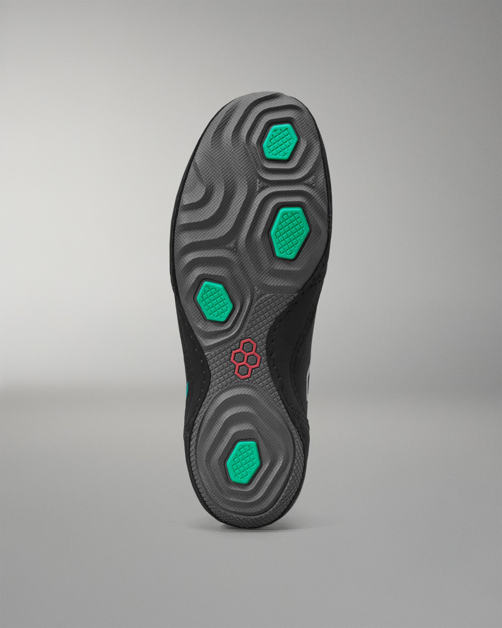 Black wrestling shoe sole with green hexagonal patterns on a gray background