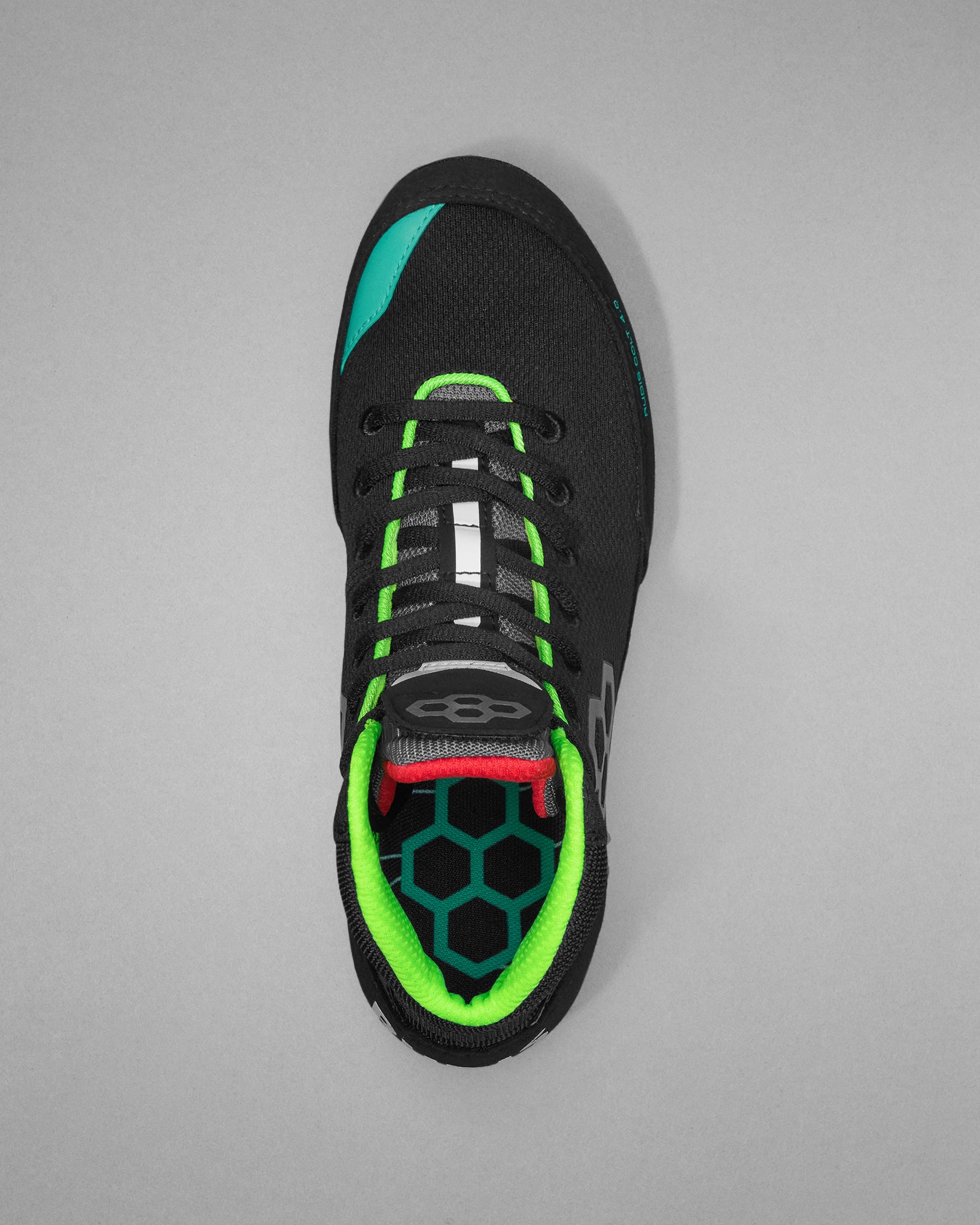 Black wrestling shoe with green and red accents on a gray background