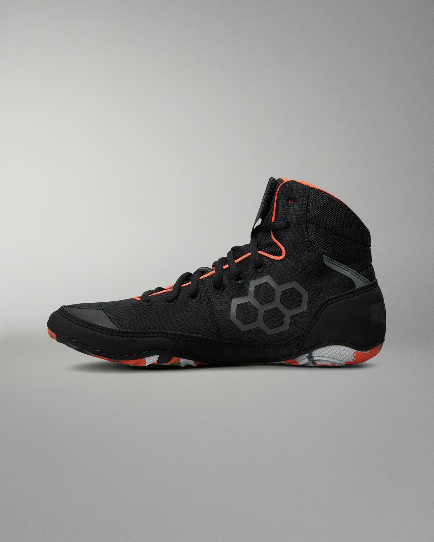A high-top Wrestling shoe in black with gray hexagonal side detailing and bright orange accents on the collar, laces, and outsole, shown against a neutral gray background.