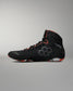 A high-top Wrestling shoe in black with gray hexagonal side detailing and bright orange accents on the collar, laces, and outsole, shown against a neutral gray background.