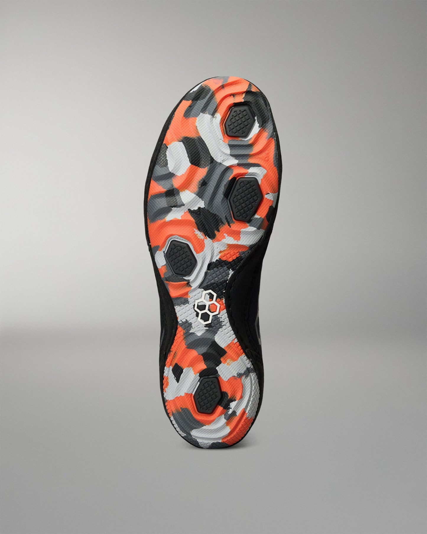 The outsole of a black Wrestling shoe featuring a vibrant orange, gray, and white geometric camouflage pattern, shown against a neutral gray background.