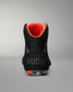 A single high-top Wrestling shoe shown from the back on a neutral gray background. The shoe is primarily black with a bright orange interior lining and a gray 'RUDIS' logo printed on the heel.
