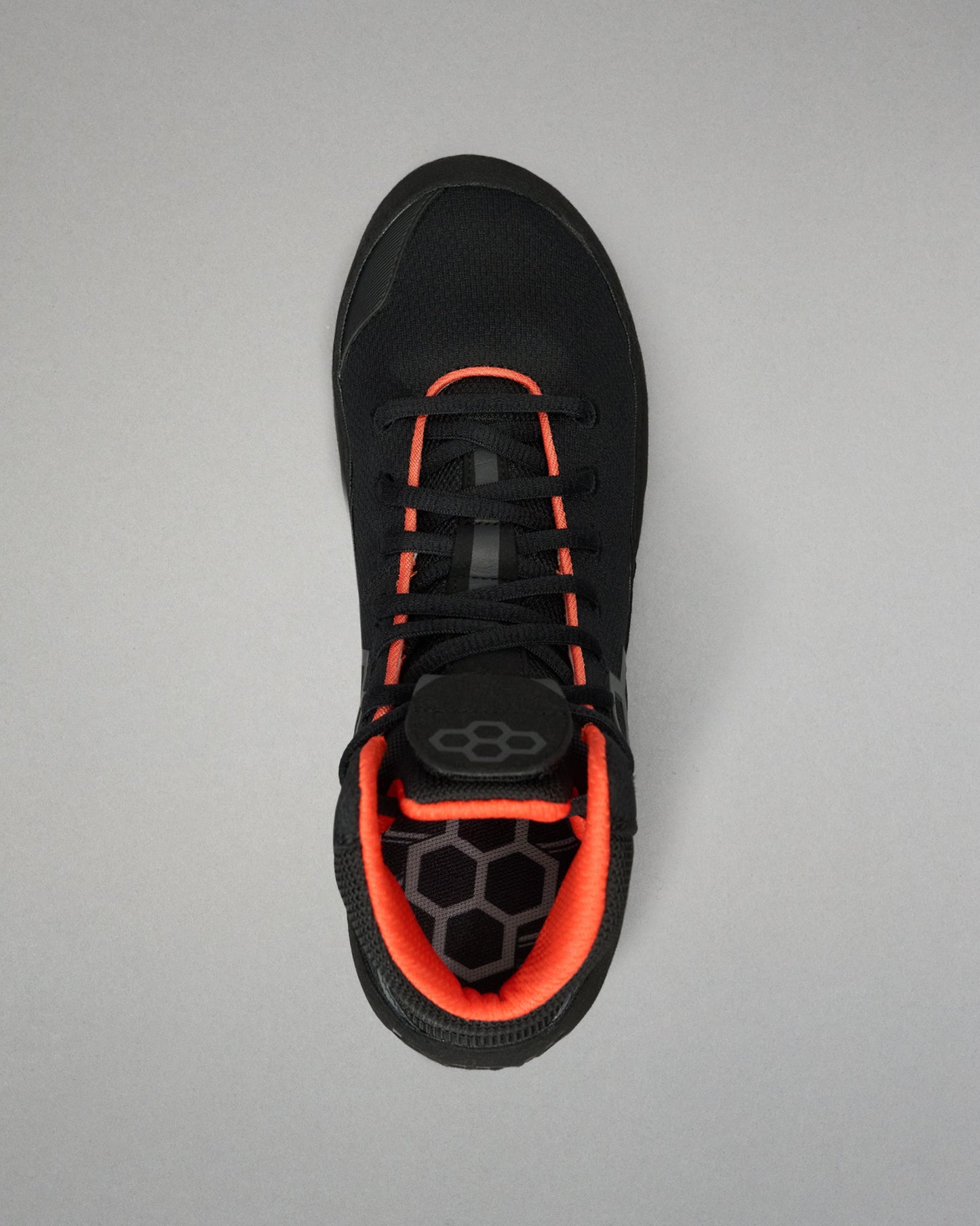 A black Wrestling shoe with vibrant orange accents, shown from a top-down view on a neutral gray background.