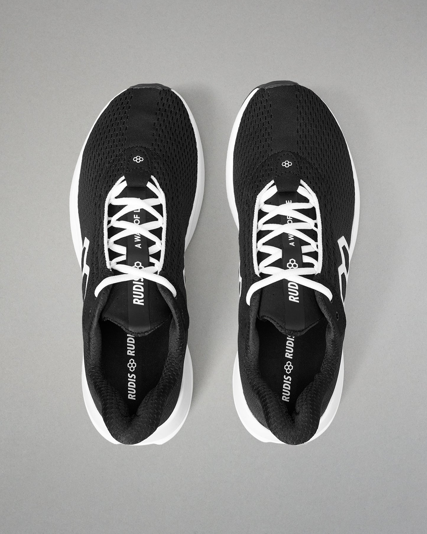 Black running shoes with white laces on a gray background