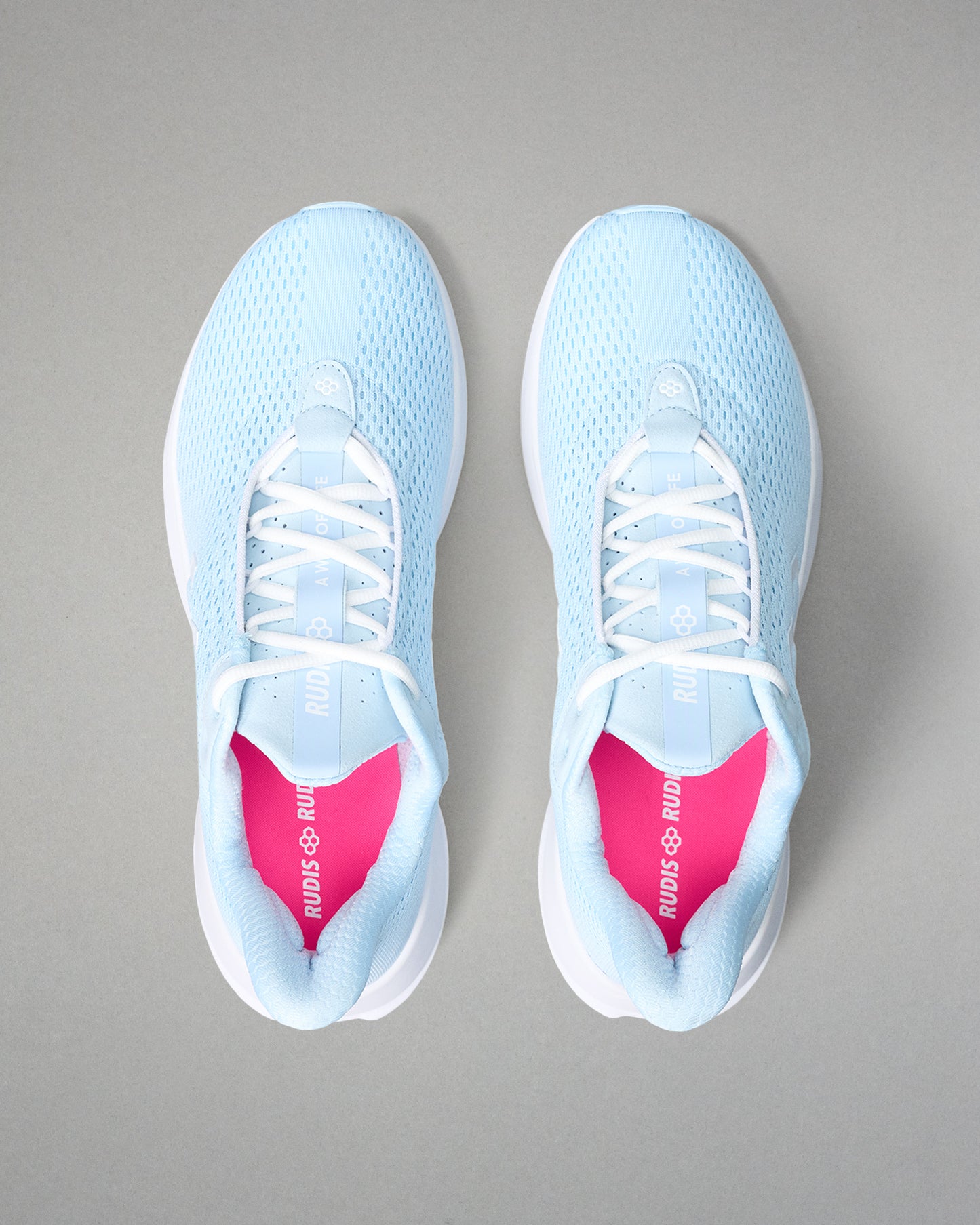 Light blue running shoes with pink insoles on a gray background