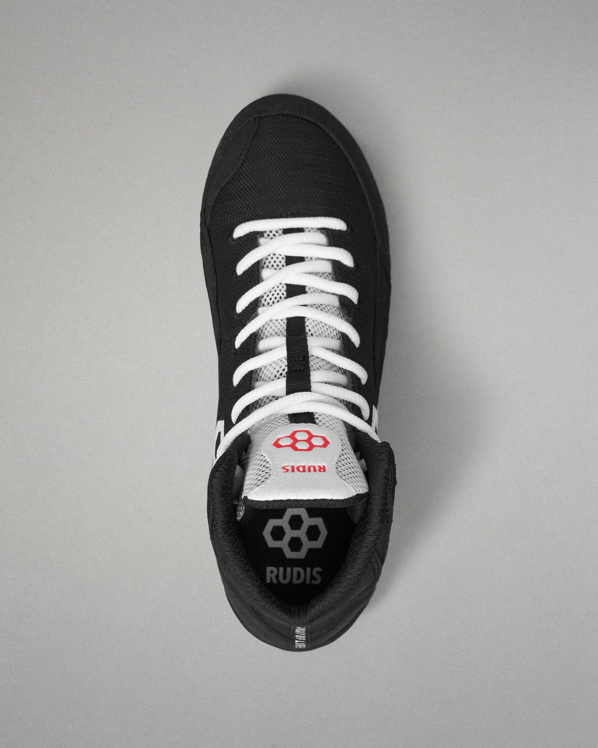 A black and white high-top wrestling shoe by RUDIS, viewed from directly above on a neutral gray background.