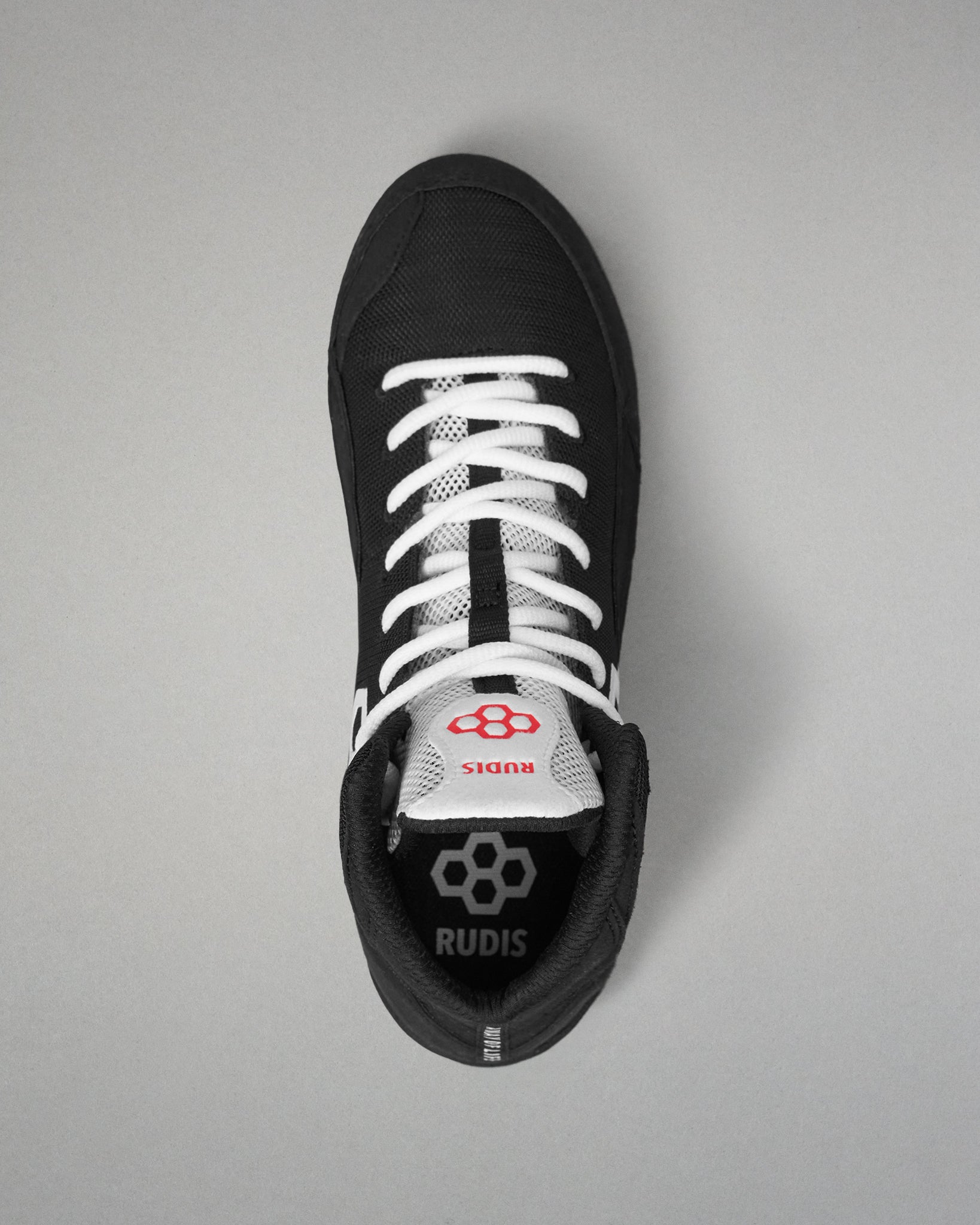 A black and white high-top wrestling shoe by RUDIS, viewed from directly above on a neutral gray background.
