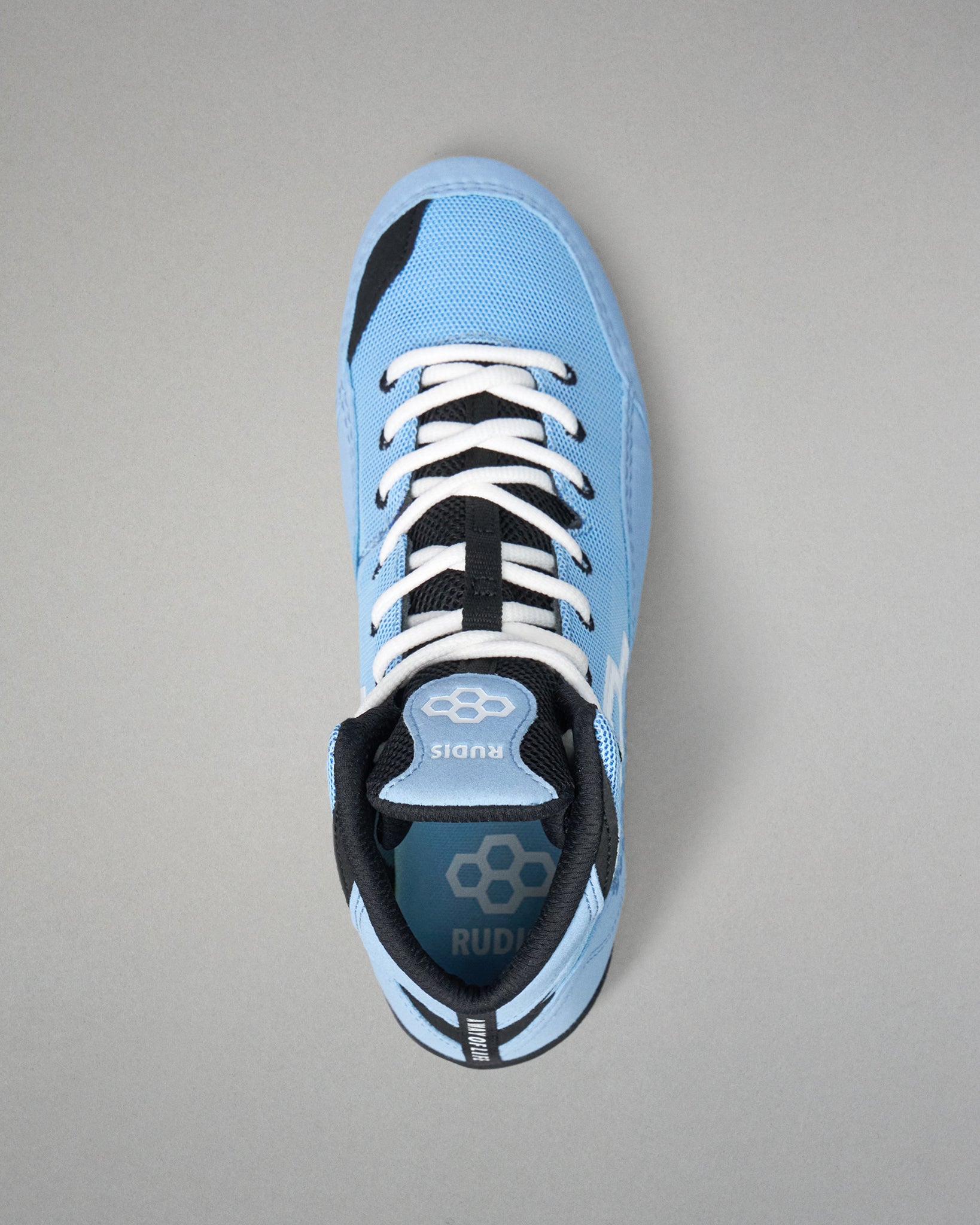 A light blue high-top wrestling shoe with black and white accents, featuring white laces and a visible RUDIS logo on the tongue and heel, photographed from a top-down angle on a neutral gray background.