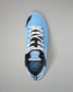 A light blue high-top wrestling shoe with black and white accents, featuring white laces and a visible RUDIS logo on the tongue and heel, photographed from a top-down angle on a neutral gray background.