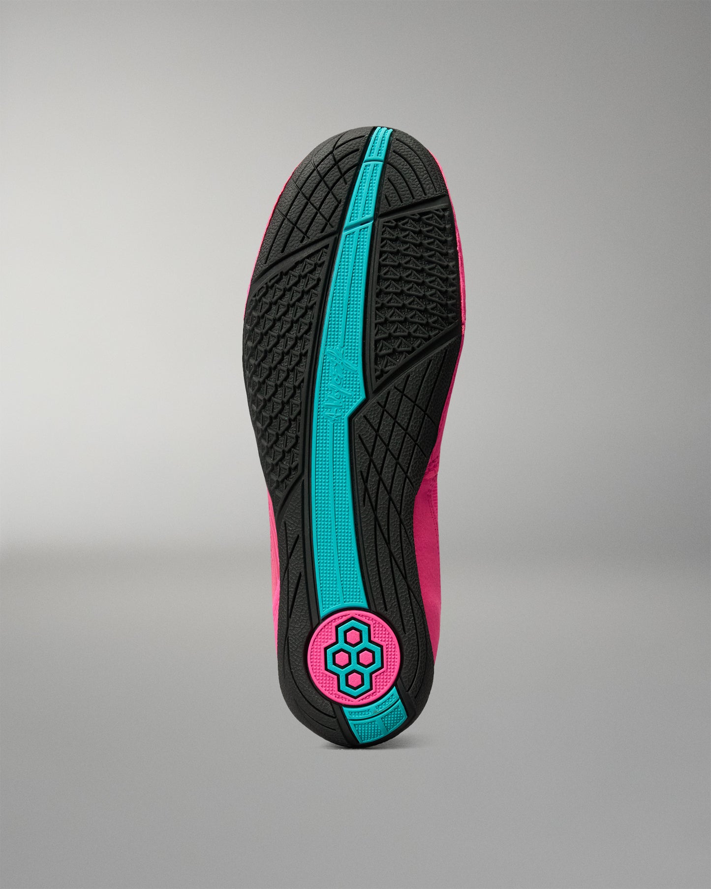 The outsole of a wrestling shoe shown from the bottom, featuring a black textured tread with a prominent bright turquoise center stripe and a circular logo patch in turquoise and hot pink at the heel.