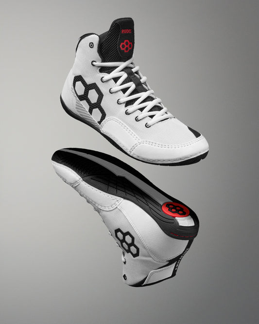 A pair of white high-top wrestling shoes with black and red accents, shown from the side and bottom angles against a gray gradient background.