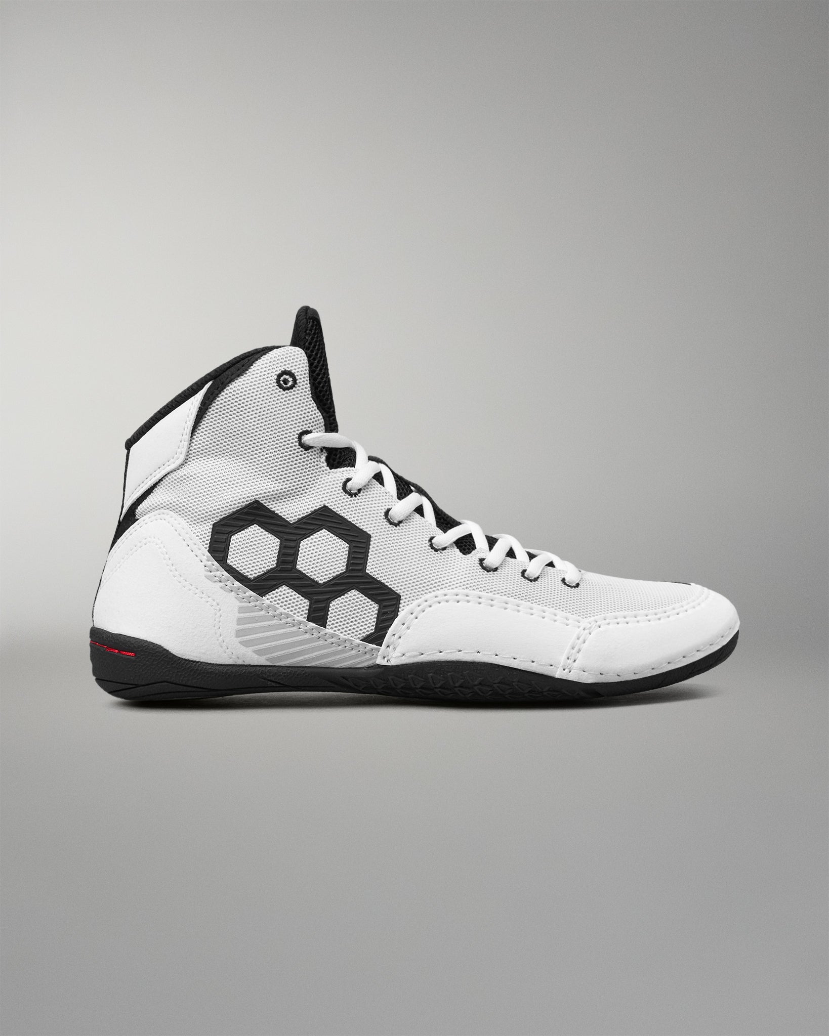 A white high-top wrestling shoe with black accents, featuring a large black geometric pattern on the side, white laces, and a black outsole, shown against a neutral gray background.