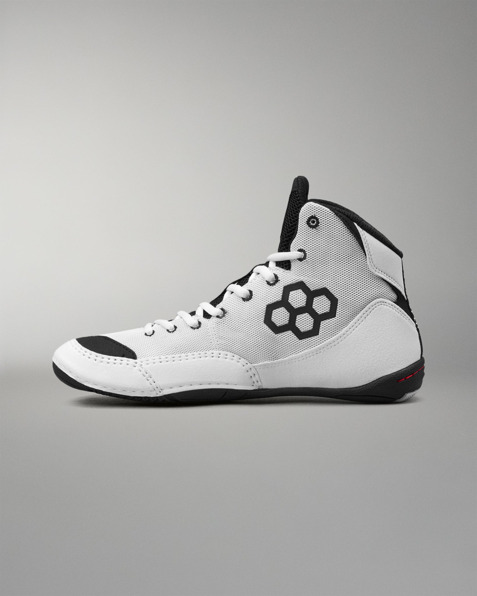 A white high-top wrestling sneaker with black accents, featuring a black geometric logo on the side, white laces, and a black outsole, shown against a neutral gray background.