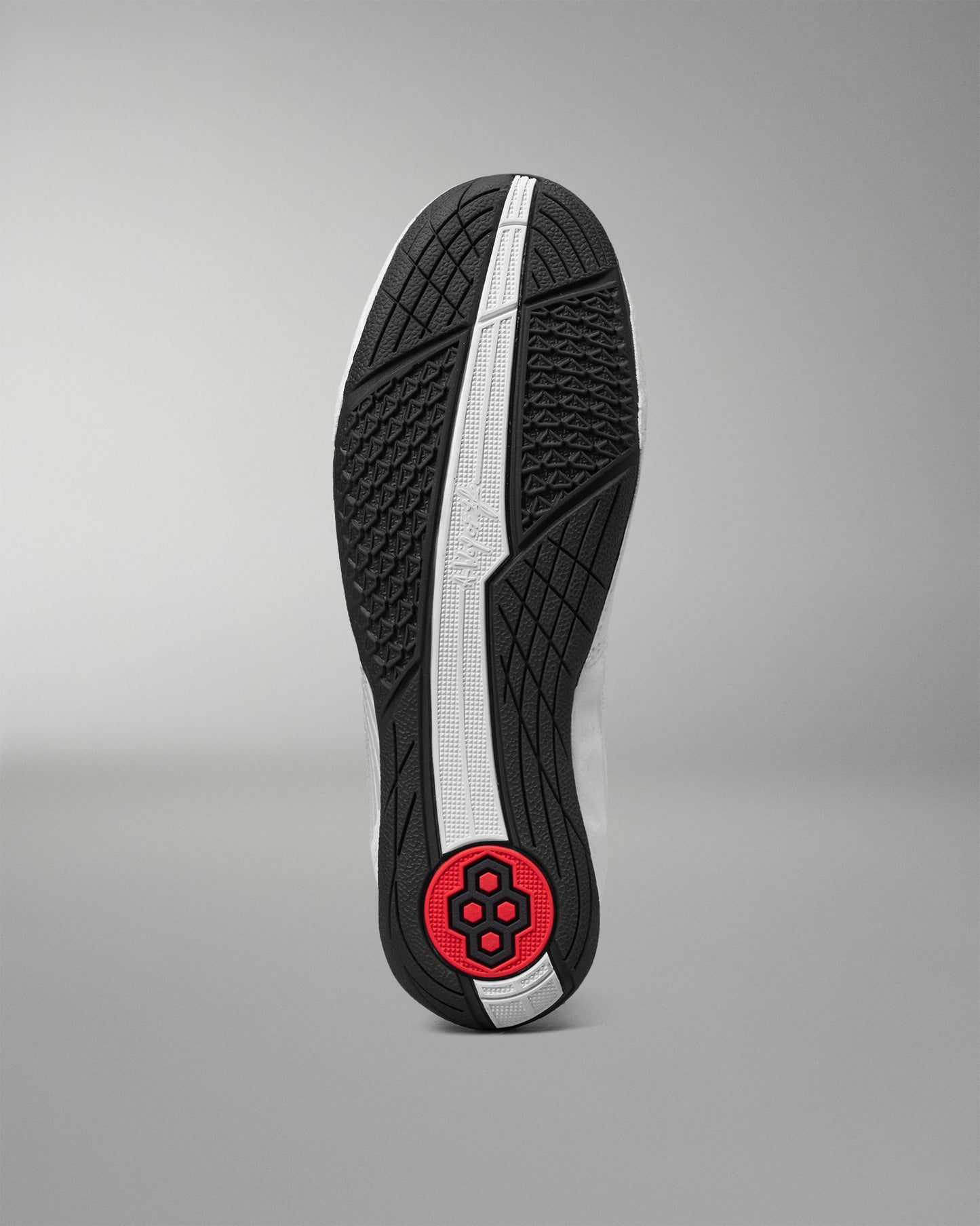 The outsole of a wrestling shoe shown from a top-down view, featuring a black textured tread pattern, a central white stripe, and a red circular heel logo on a gray gradient background.