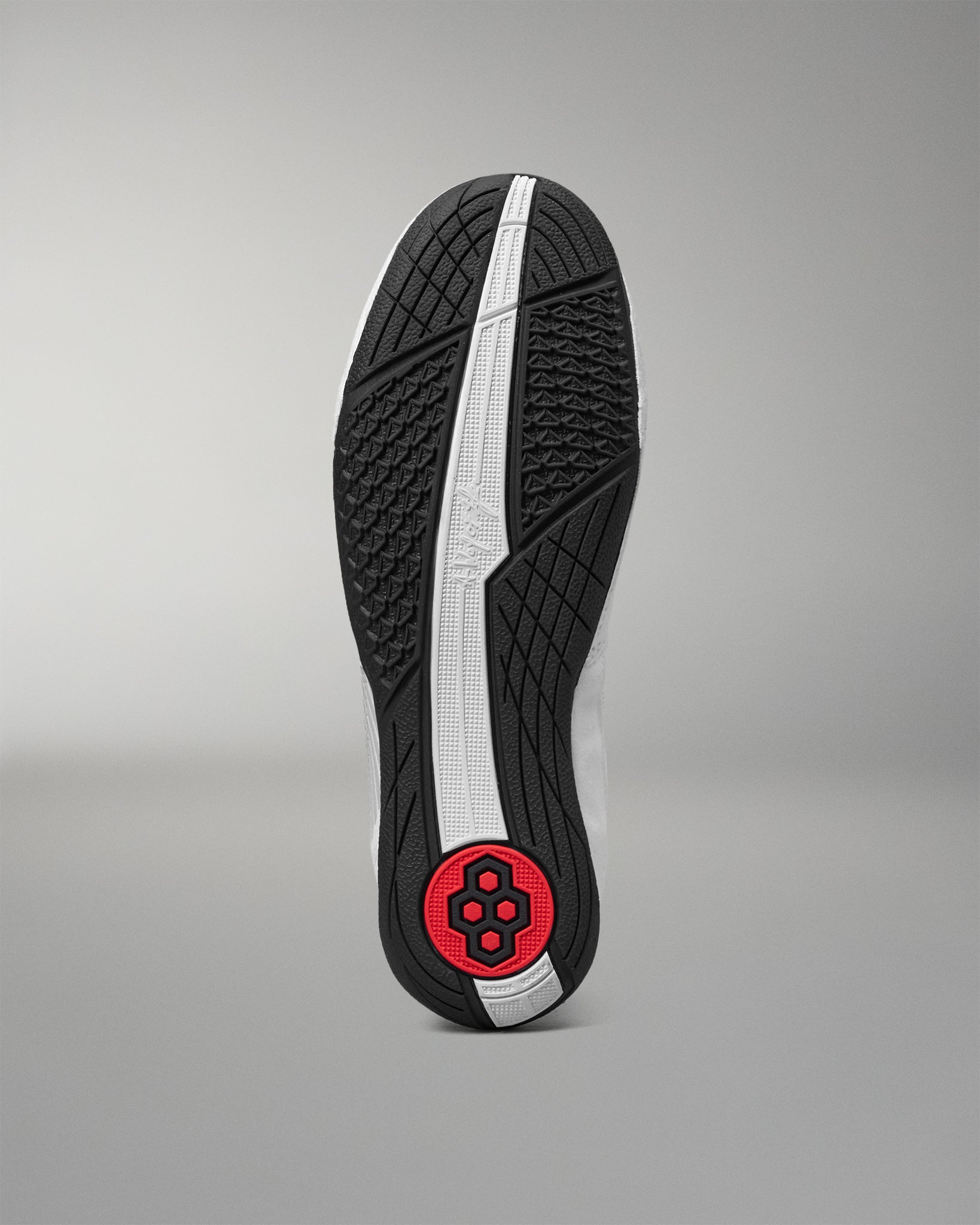 The outsole of a wrestling shoe shown from a top-down view, featuring a black textured tread pattern, a central white stripe, and a red circular heel logo on a gray gradient background.