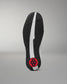 The outsole of a wrestling shoe shown from a top-down view, featuring a black textured tread pattern, a central white stripe, and a red circular heel logo on a gray gradient background.