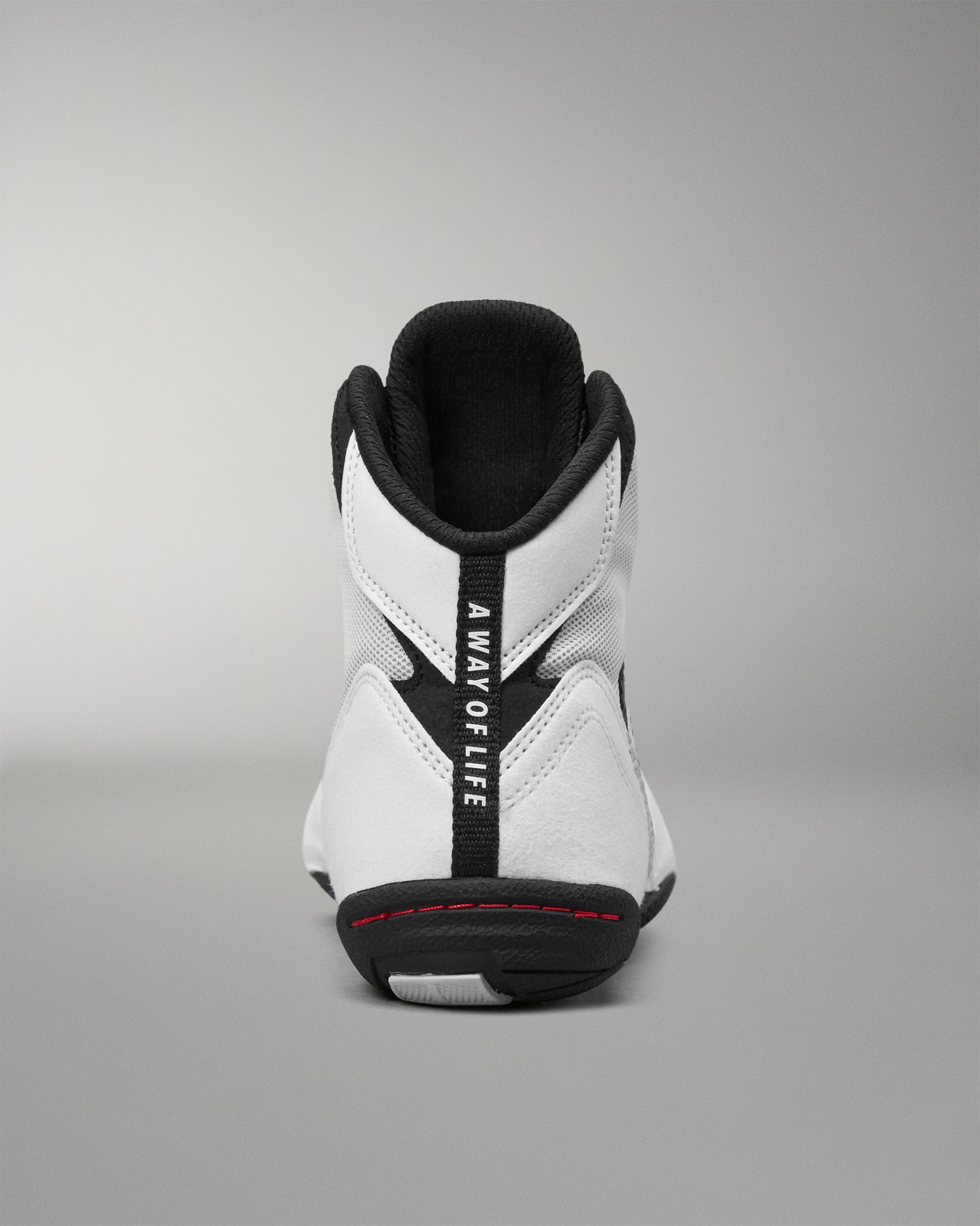 A high-top wrestling shoe shown from the back, featuring a white leather and mesh upper with black accents, including a black heel tab with the vertical text 'A WAY OF LIFE' and a black outsole.