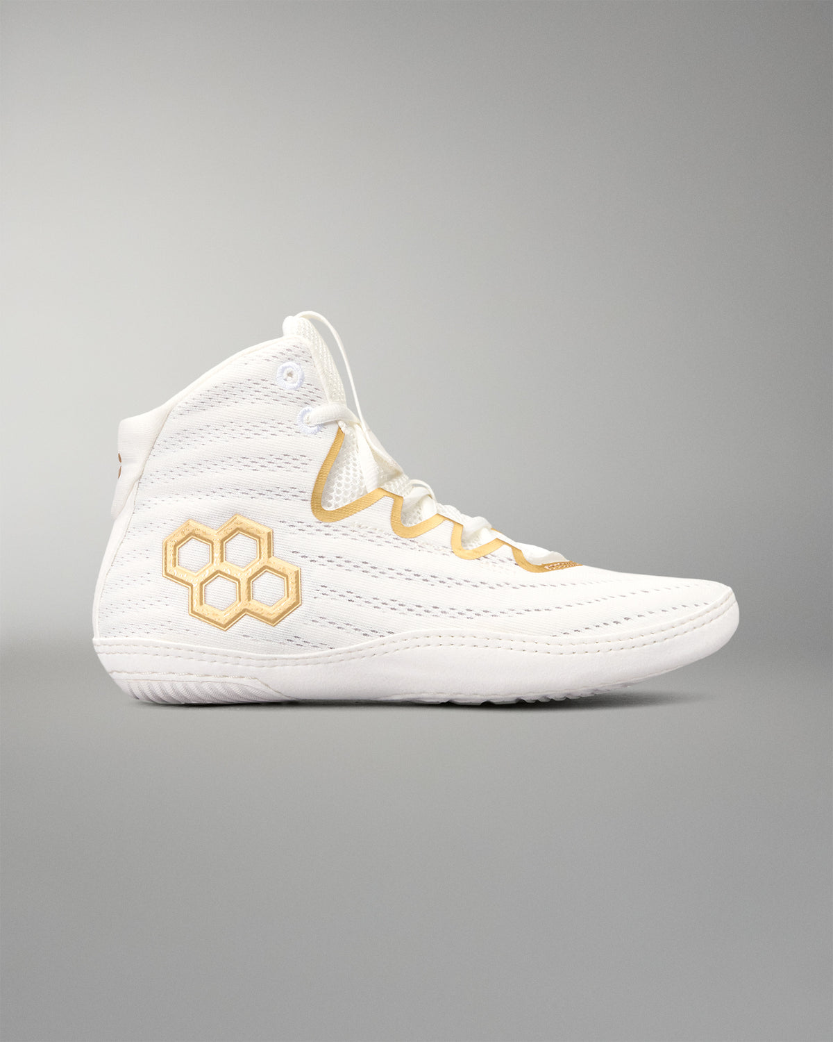 A white wrestling shoes with gold accents, featuring a gold quadhex logo on the side and gold embroidered details around the eyelets, shown against a neutral gray background.