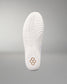 The white outsole of a wrestling shoe, showing textured tread patterns and a small gold geometric logo near the heel, set against a neutral gray background.
