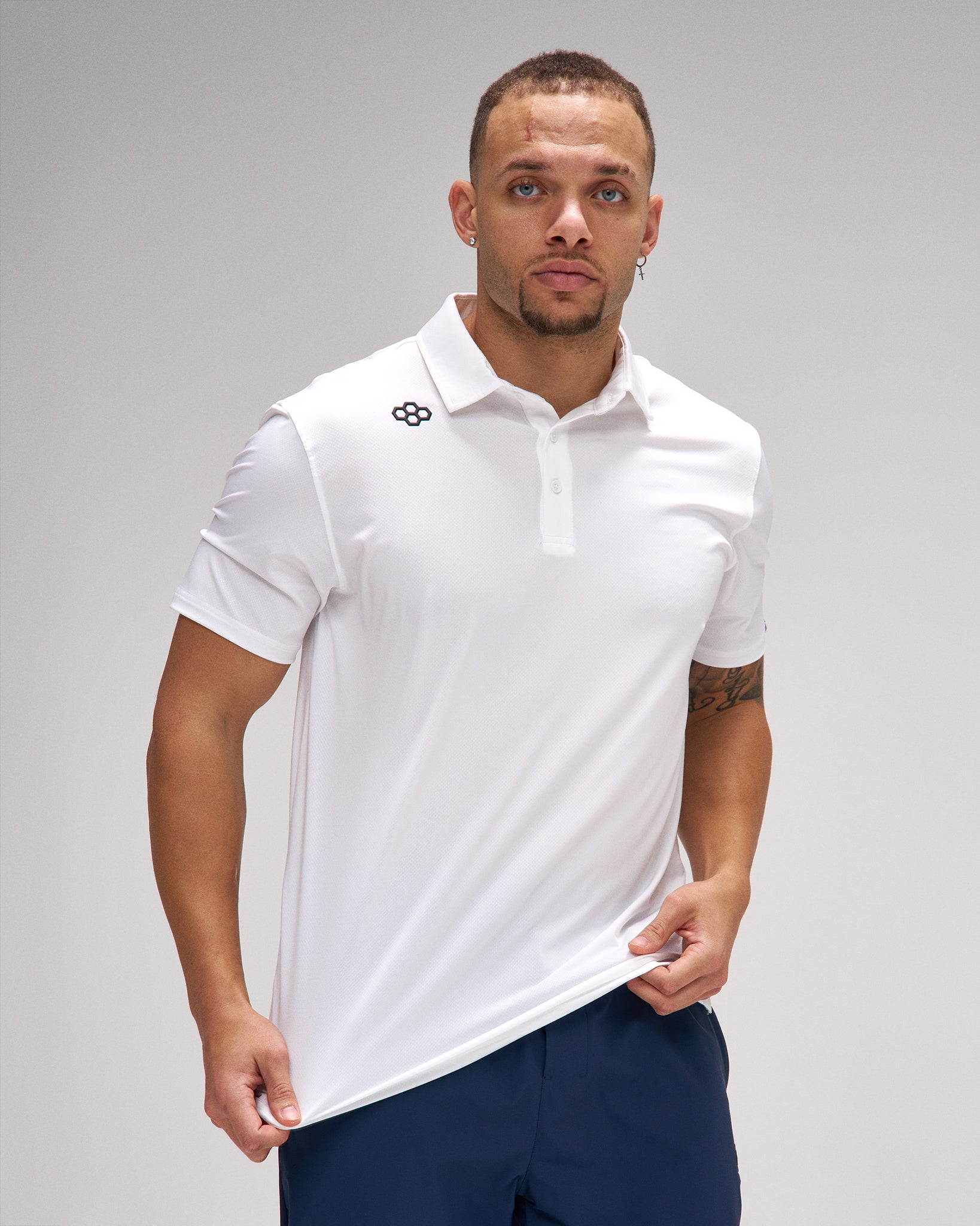 Man wearing a white polo shirt with a logo on a gray background