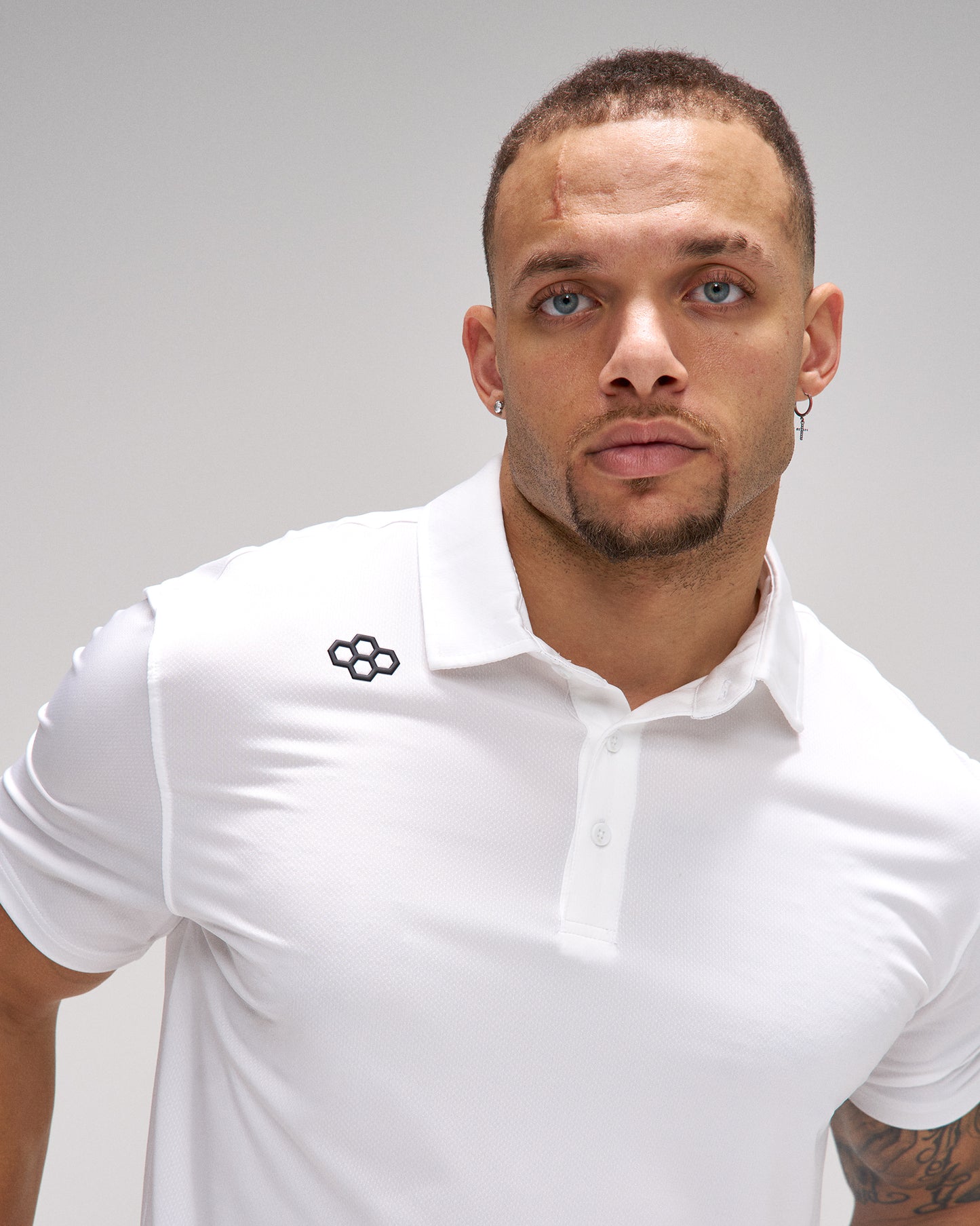 Man wearing a white polo shirt with a logo on a gray background