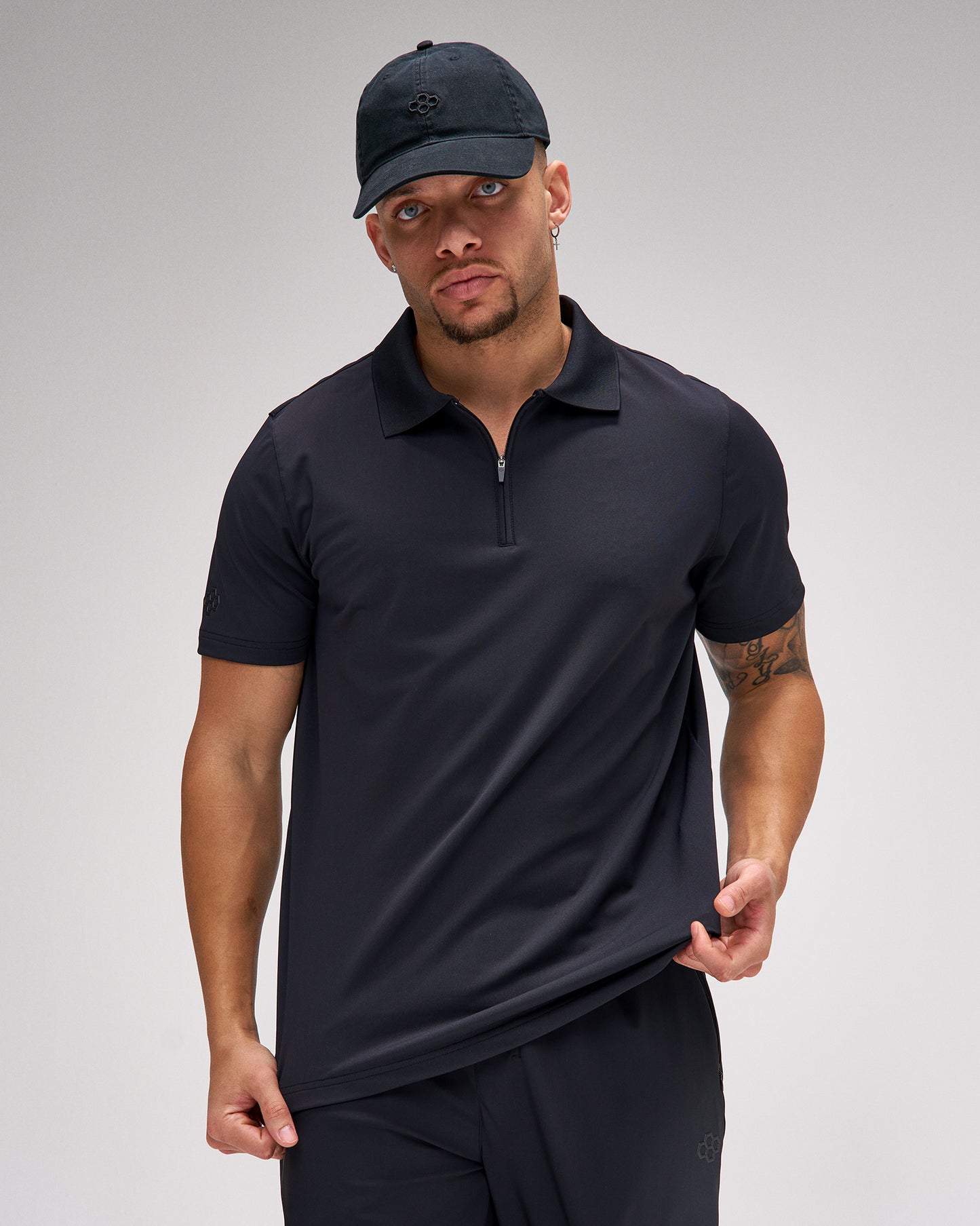 Man wearing a black polo shirt and cap on a gray background
