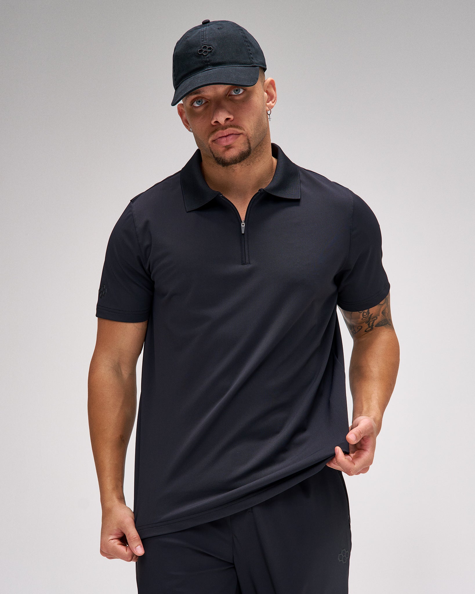 Man wearing a black polo shirt and cap on a gray background