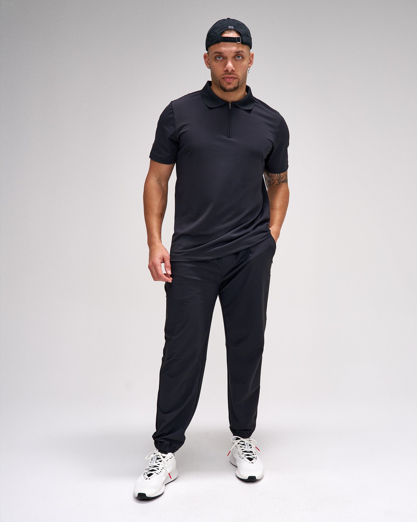 Man wearing a black outfit with a cap on a white background