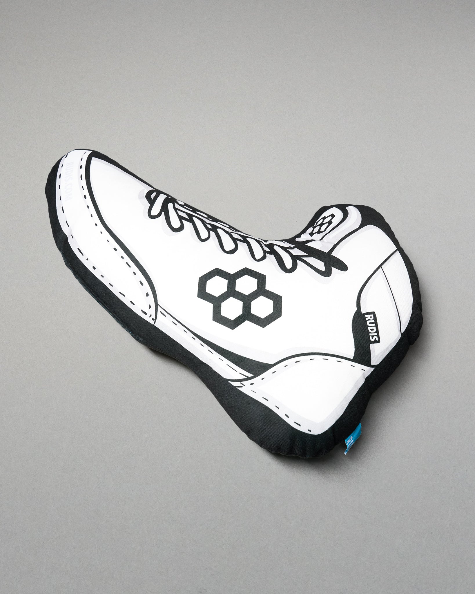 White shoe-shaped pillow with black accents on a gray background