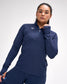 Woman wearing a navy long-sleeve athletic top with a logo on a white background