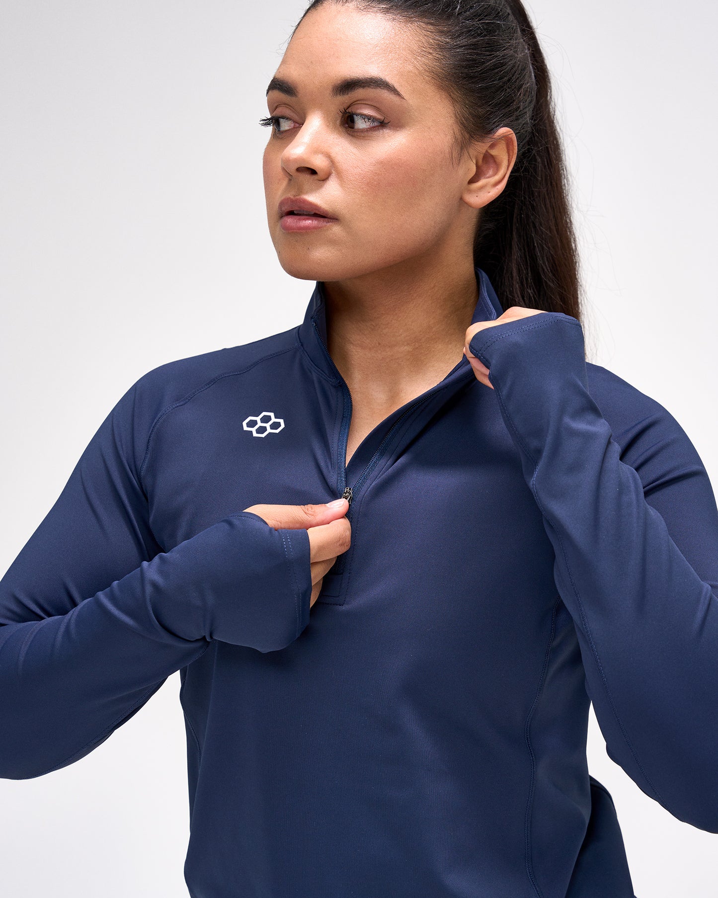 Woman wearing a navy blue athletic jacket with a logo on a light gray background