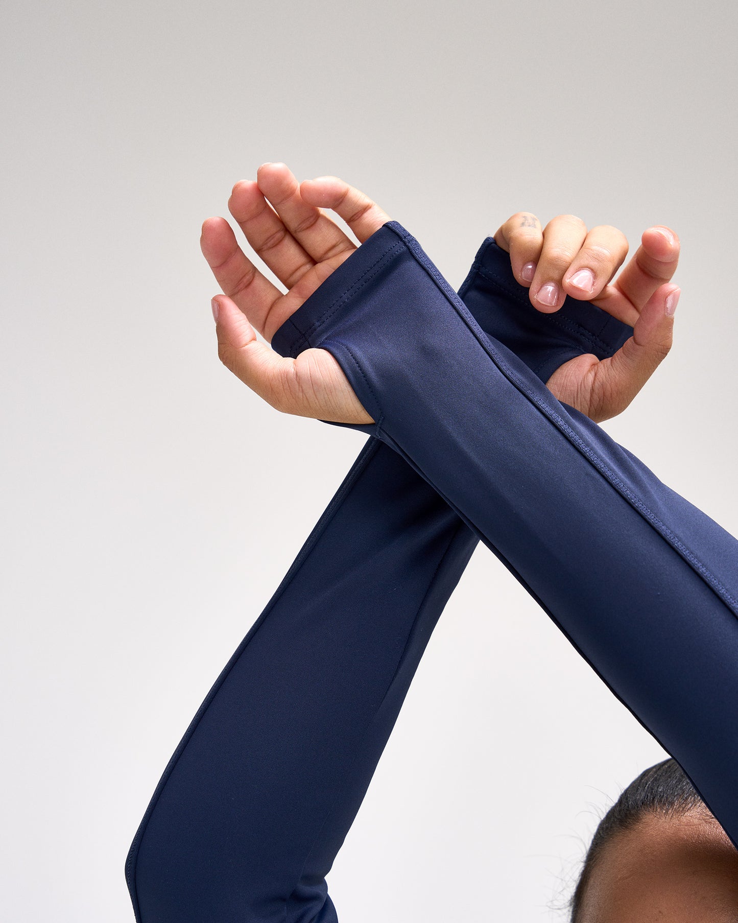 Person wearing a navy blue sleeve on one arm against a light gray background