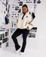 Model wearing the RUDIS Women's Sherpa Half Zip in White/Black with black leggings, showcasing the relaxed fit, half-zip collar, contrast piping and front pockets.