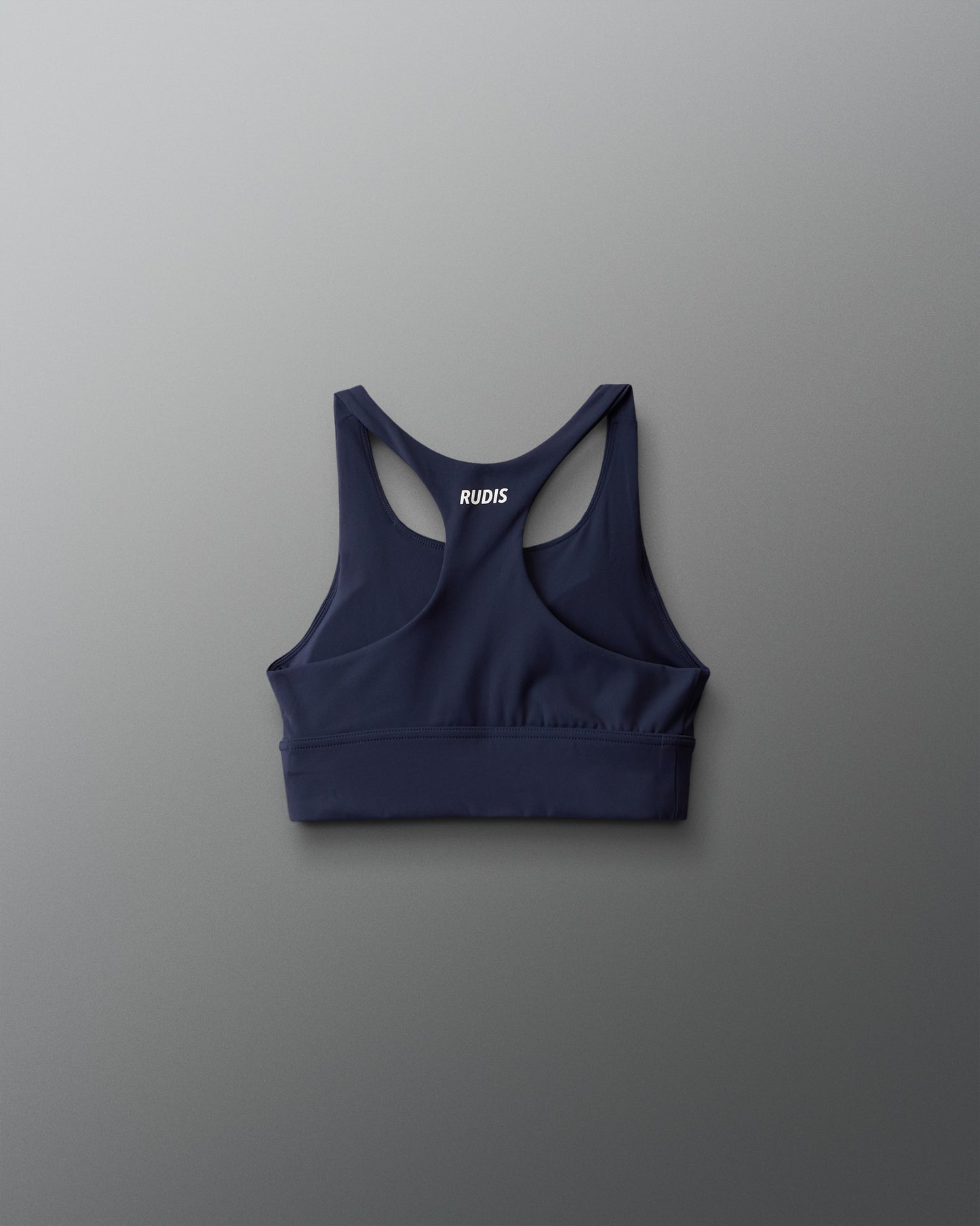 Navy blue sports bra with 'RUDIS' branding on a gray background