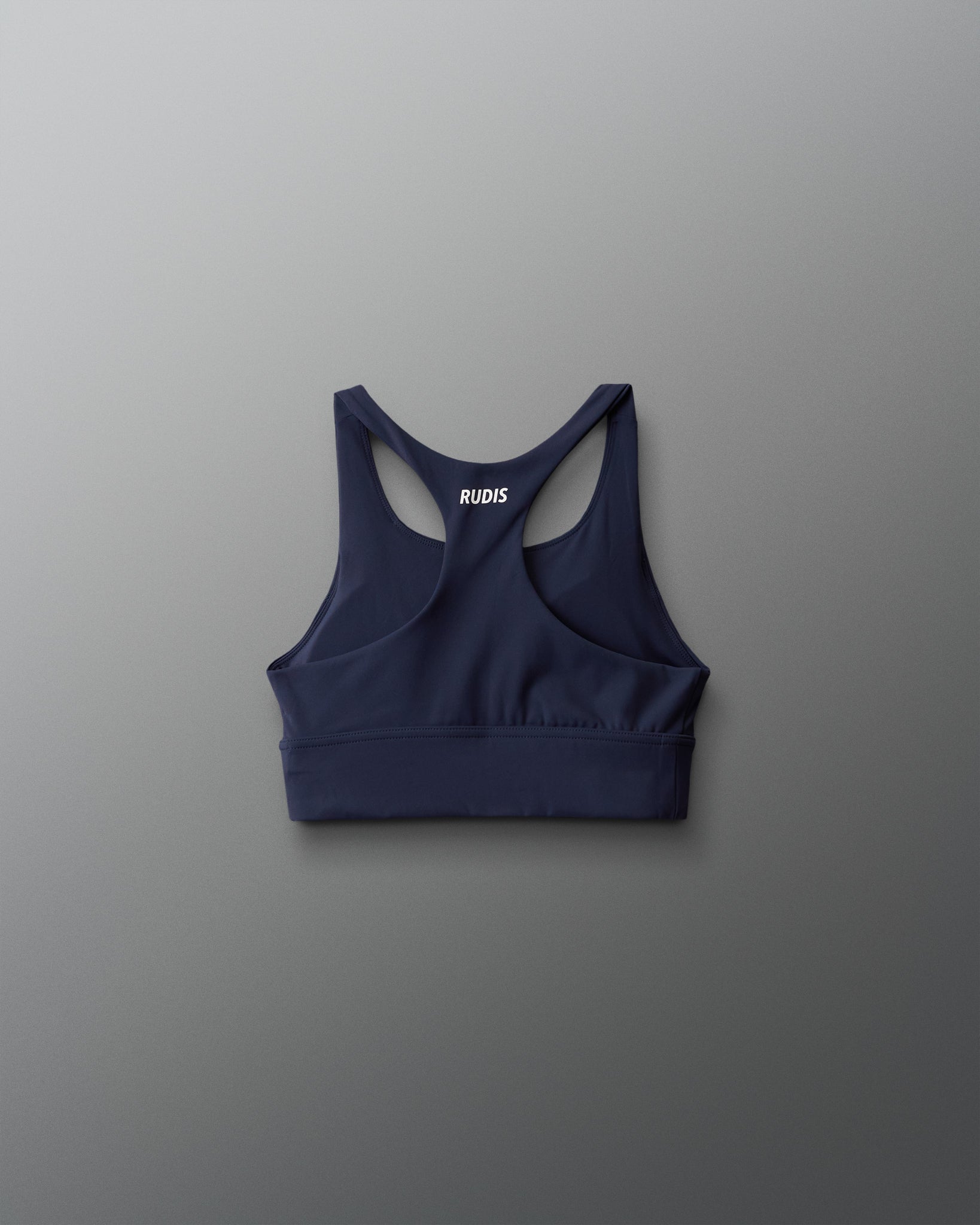 Navy blue sports bra with 'RUDIS' branding on a gray background